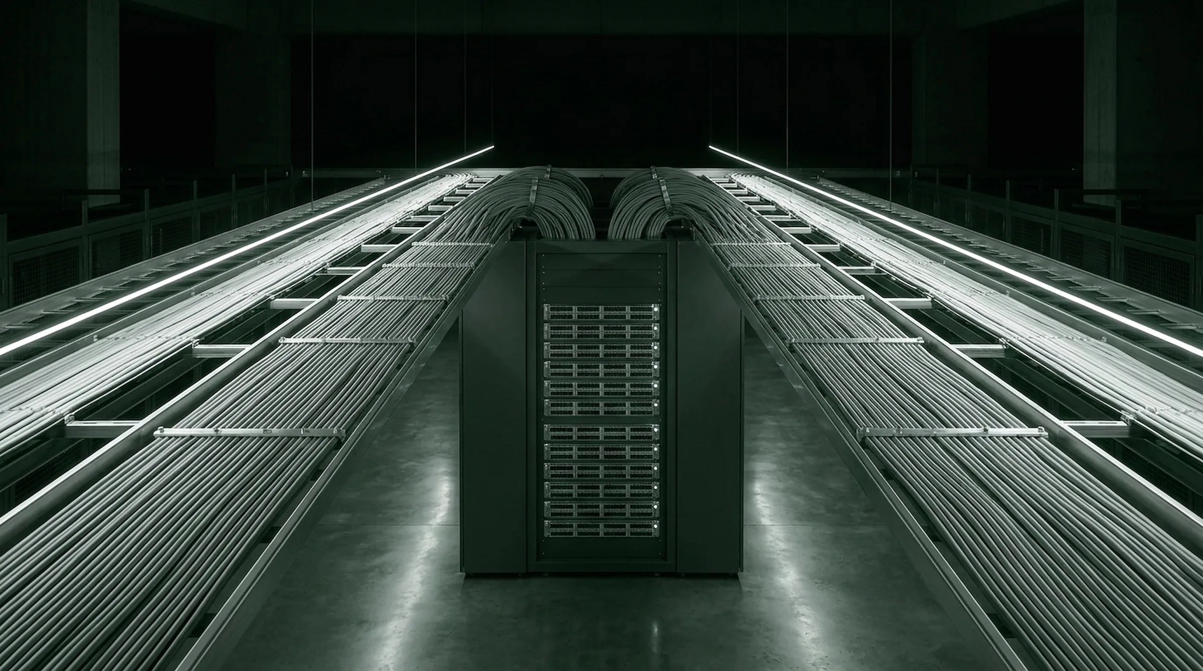 Bundled InfiniBand cabling sweeping along overhead trays into a central switch rack in a dark data hall
