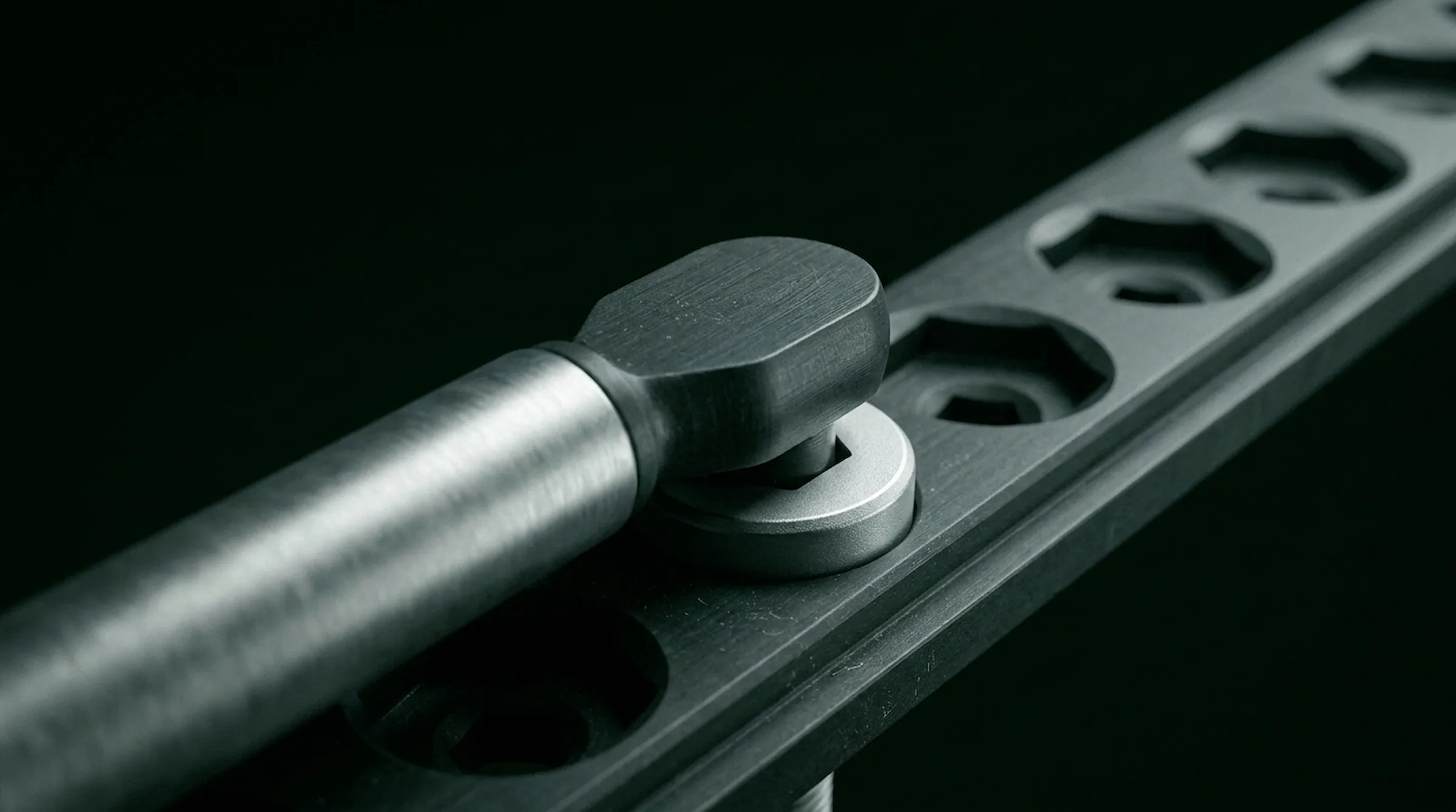 Macro of a torque wrench seating a bolt on a server rack rail under workshop light
